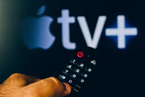 Apple TV Plus logo with a close-up of a hand holding a remote control