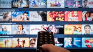 TV television displaying streaming content with hand holding a remote in the foreground