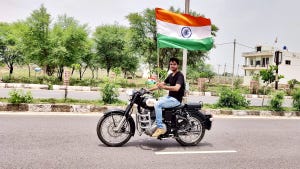 Man on a motorcycle holding the Indian Flag