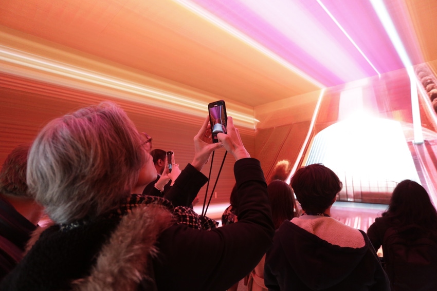 A woman takes a photo on her smartphone at MWC 