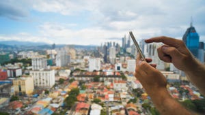 Hands using a smartphone in foreground, city in background