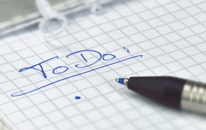 To-do list written on slip of graph paper in blue pen