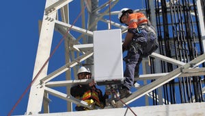 Ericsson engineer putting radio equipment on a mast.