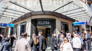 Several people walking around outside a Telstra storefront