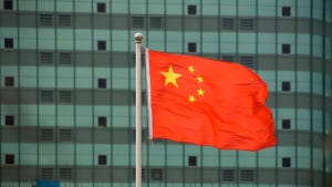 Chinese Flag Fluttering in the wind in the shadow of Modern Office Blocks in the Guangdong Region of China