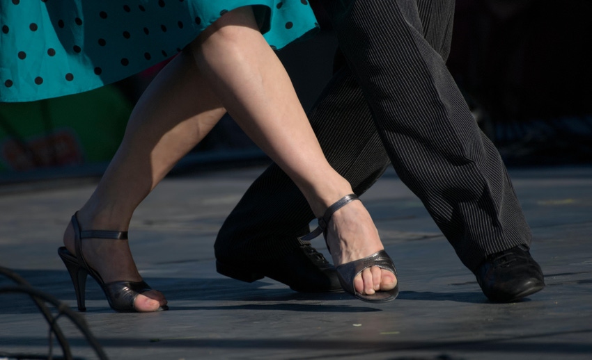 Woman and man tango dancers synchronize their foot movements during a tango exhibition