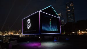 Illuminated house at night bearing Three's logo