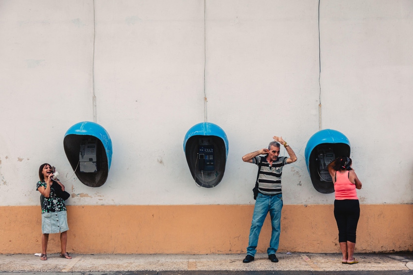 People talking on old payphones in Havana
