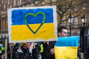 A person holding a sign painted like the Ukraine flag with a heart over it A person holding a sign painted like the Ukraine flag with a heart over it