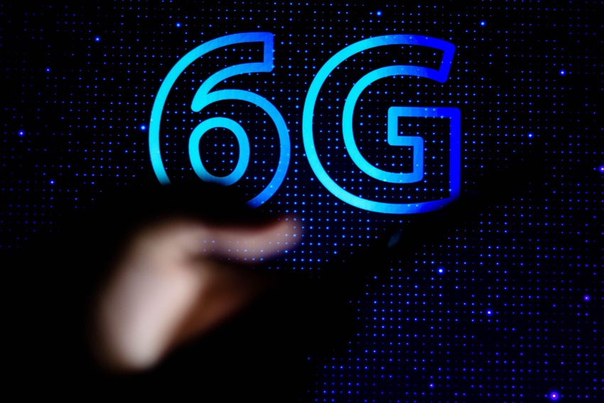 Photo illustration of a person holding a mobile phone with a 6G logo in the background