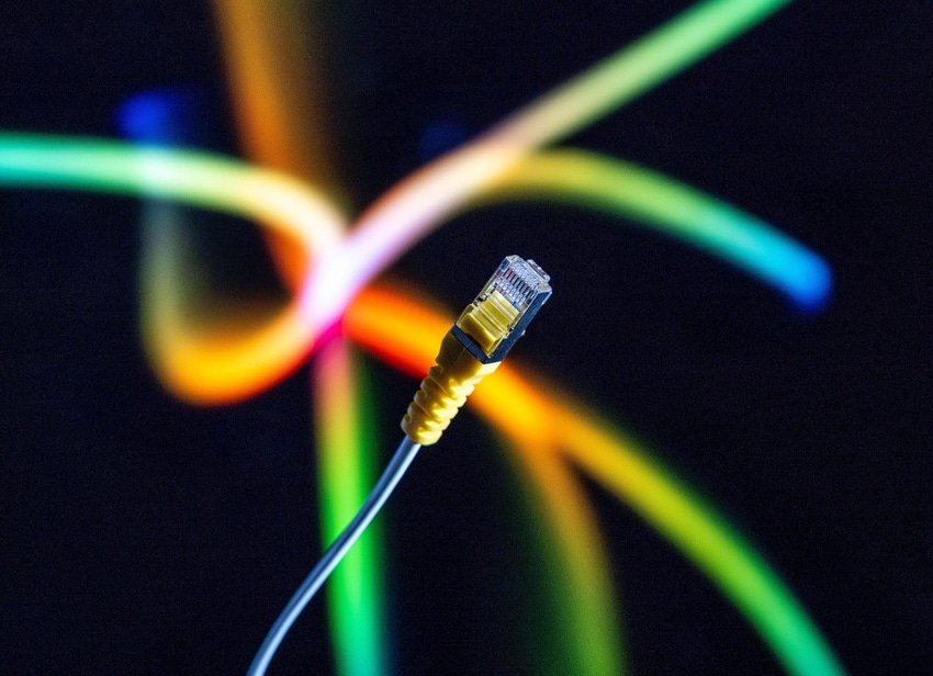 Internet cable and yellow ethernet connector in close up against a colorful background