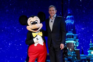 Disney Chairman and CEO Bob Iger, right, poses with an entertainer dressed in a costume of Micky Mouse during a launch ceremony.