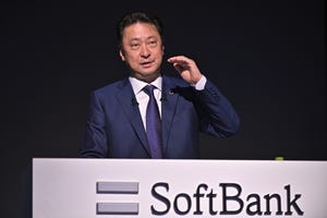 SoftBank CEO Junichi Miyakawa presenting the company's earnings results with the company's logo in front of him and a dark background behind him.