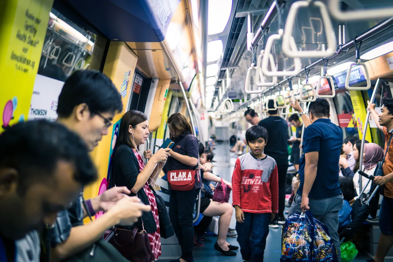 Riders on Singapore MRT using smartphones Riders on Singapore MRT using smartphones