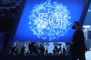 A visitor walks past a 5G logo at Mobile World Congress MWC