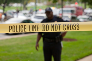 Policeman standing behind police line tape at a crime scene - Washington, DC USA