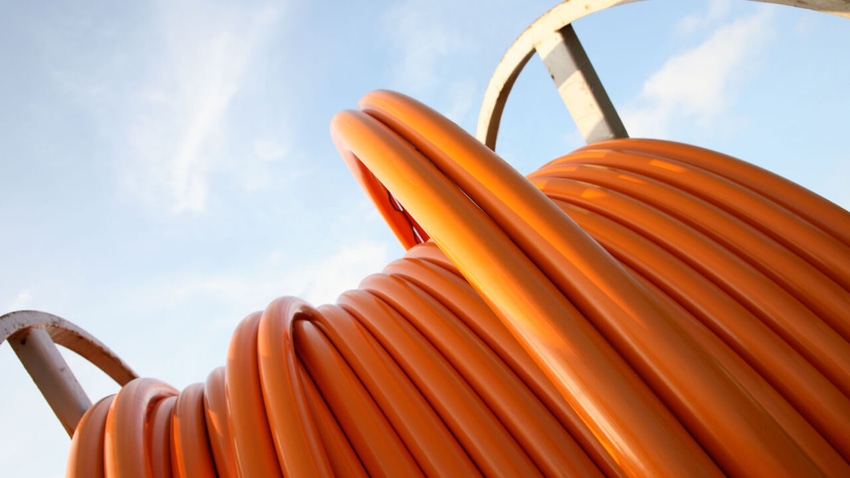 Orange cable for broadband connections on a steel cable drum against a blue sky
