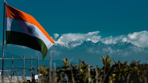 Indian flag above a field, with mountains in the background