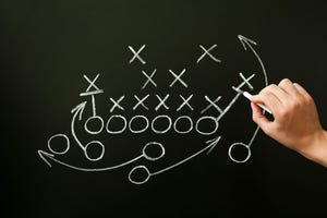 Coach drawing American football or rugby game play on a chalkboard 