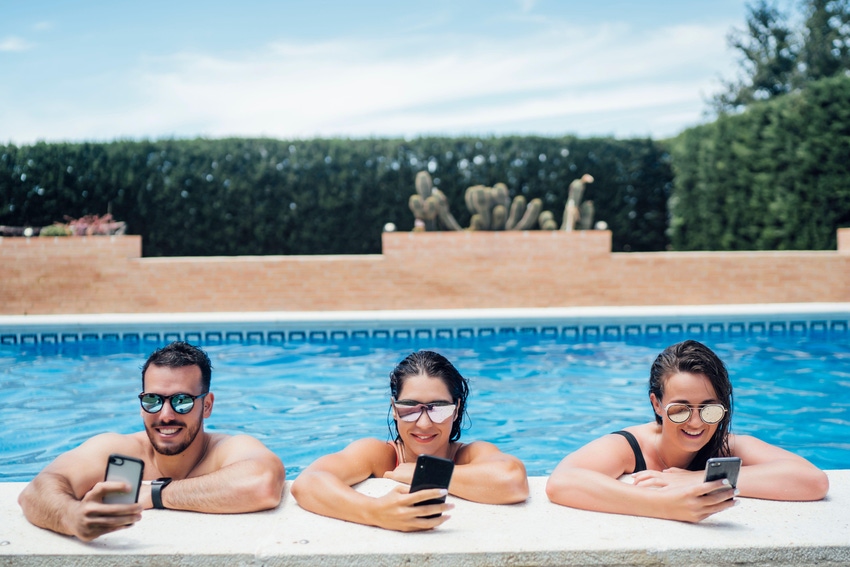 Friends during pool party using smartphones