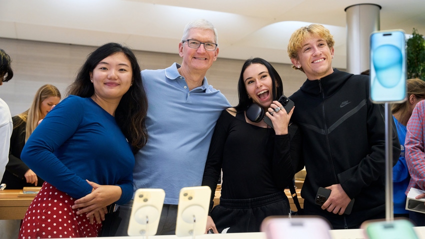 Tim Cook of Apple stands next to iPhone customers in a store