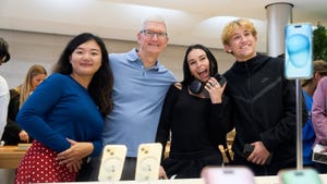 Tim Cook of Apple stands next to iPhone customers in a store