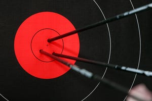 Three arrows in center of a black and red archery target 