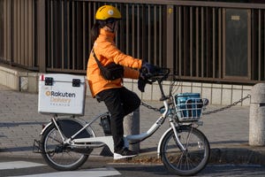 A woman rides a bicycle for Rakuten Delivery company.