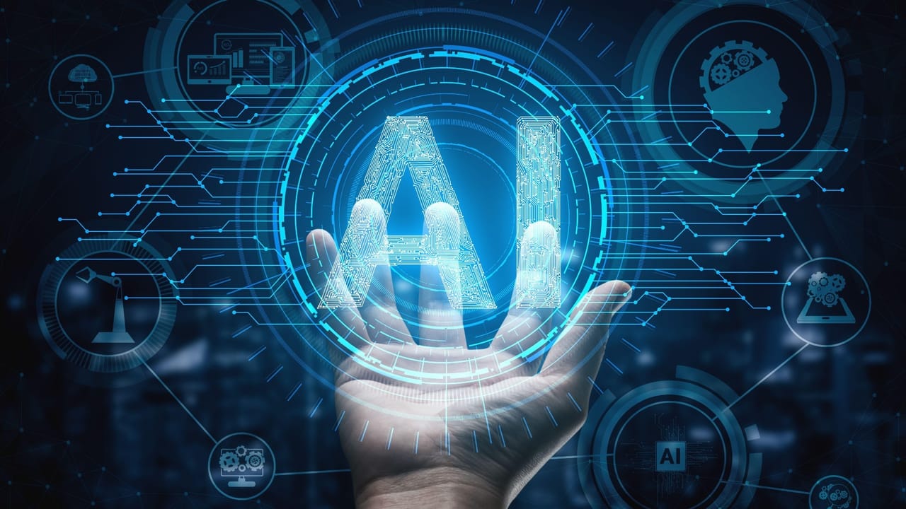 The word AI made out of circuits overlaid with a photo of an outstretched hand, appearing as though the person is holding the graphic The word AI made out of circuits overlaid with a photo of an outstretched hand, appearing as though the person is holding the graphic