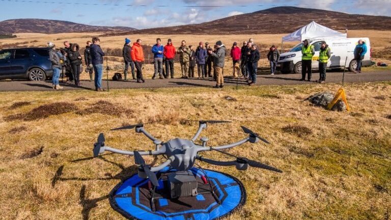 A drone on the ground with people in the background.