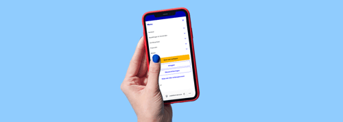 A hand holding a mobile phone against a blue background