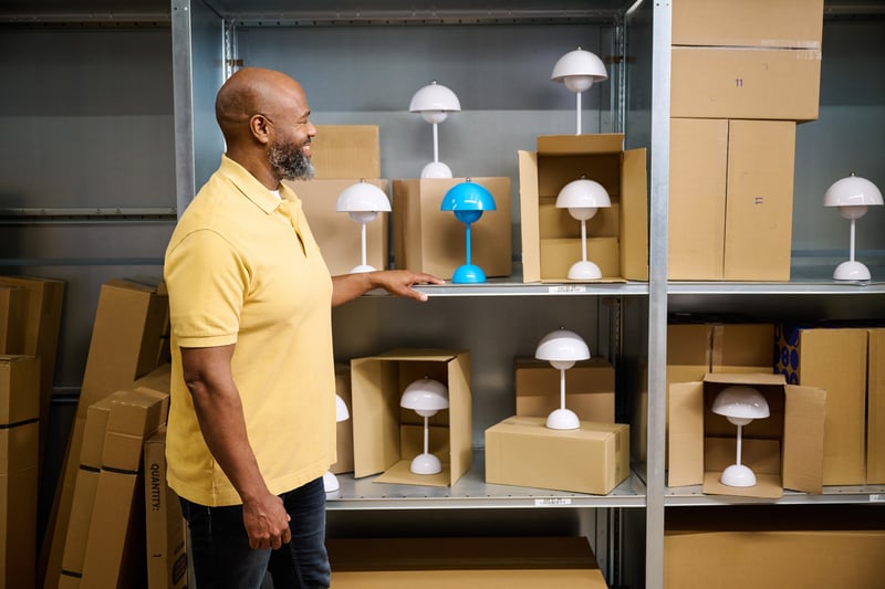 Een man staat naast een kast met meerdere witte en een blauwe lamp. 