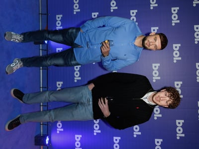 Twee mannen staan op een blauw tapijt tijdens een evenement van bol.com.