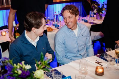 Twee mensen in gesprek tijdens een formeel diner, warm glimlachend