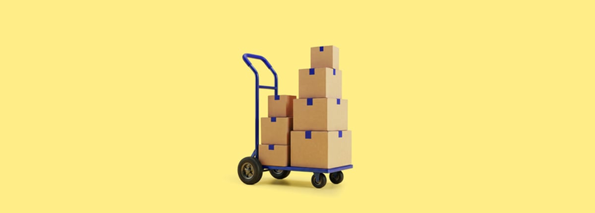 A hand truck loaded with several stacked cardboard boxes against a solid yellow background.