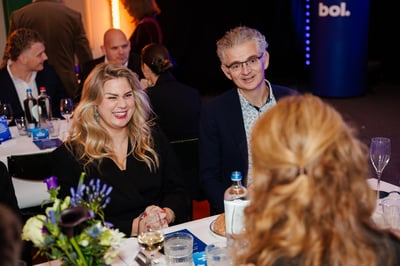 Een levendige sociale bijeenkomst met mensen die aan een tafel zitten, in gesprek zijn en lachen. 