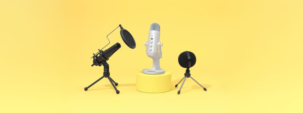 Three microphones on a yellow background: a white microphone on a stand in the center, a black microphone with a pop filter on the left, and a small black microphone on the right.