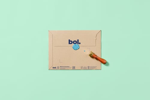 A decorative envelope with a blue circular pattern and a wax seal lies on a mint green background. A sealing stamp with a wooden handle is next to it.