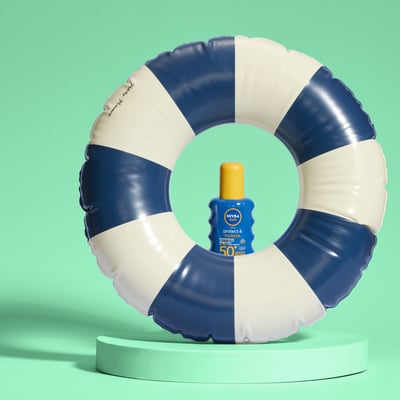 Zwemband met een flesje zonnebrandcreme erachter op een groene achtergrond.