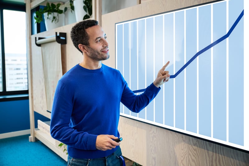 Een man staat voor een scherm met een opwaardse trend.