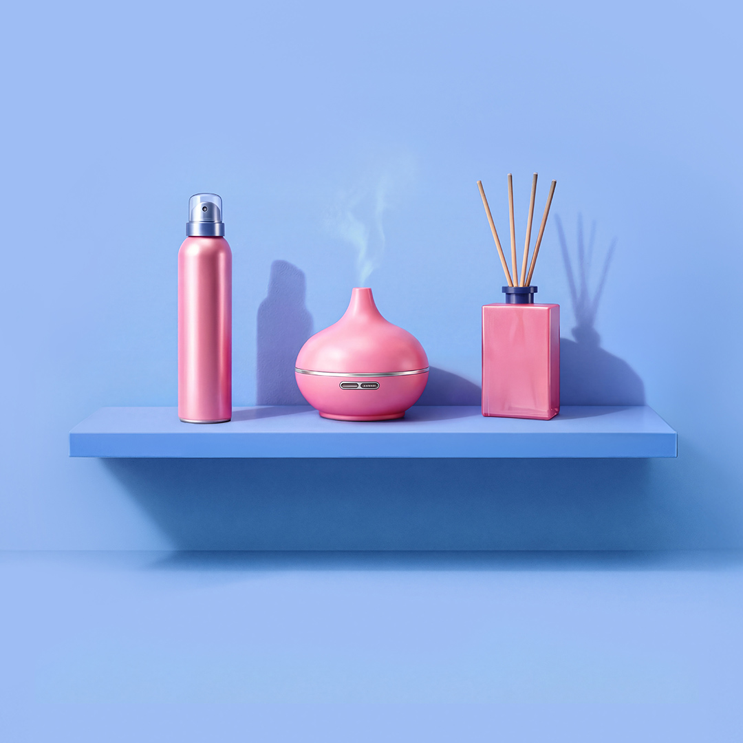 Een minimalistische compositie met een roze waterfles, een diffuser die damp verspreidt en een rietdiffuser op een blauwe plank tegen een levendig blauwe achtergrond.