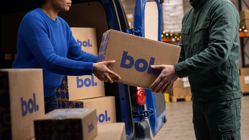 Twee warehousemedewerkers pakken een bezorgbus aan kartonnen dozen uit.