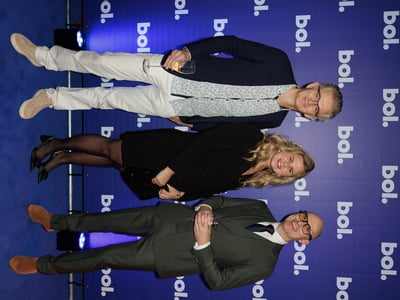Drie mensen poseren tijdens een evenement met een blauw thema.