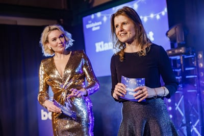 Twee vrouwen staan op het podium tijdens een evenement