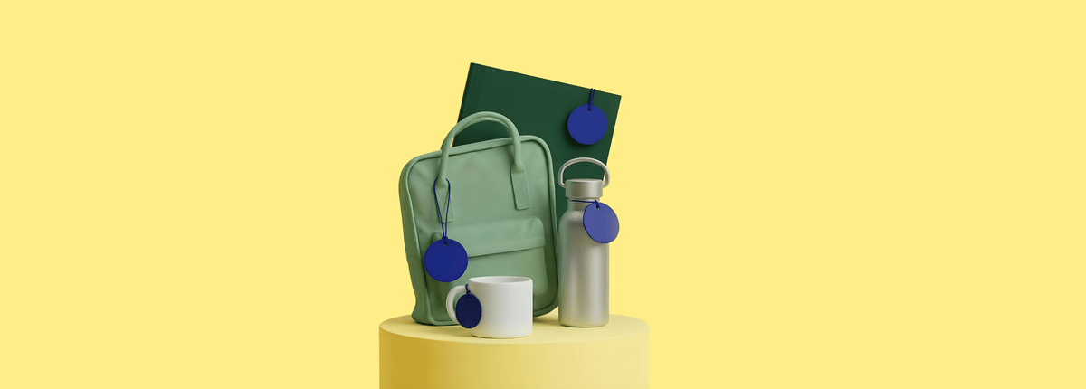 Een mintgroene tas, een zilverkleurige waterfles, een witte mok en een donkergroen boek. Elk item heeft een blauw label en staat op een geel voetstuk tegen een gele achtergrond.