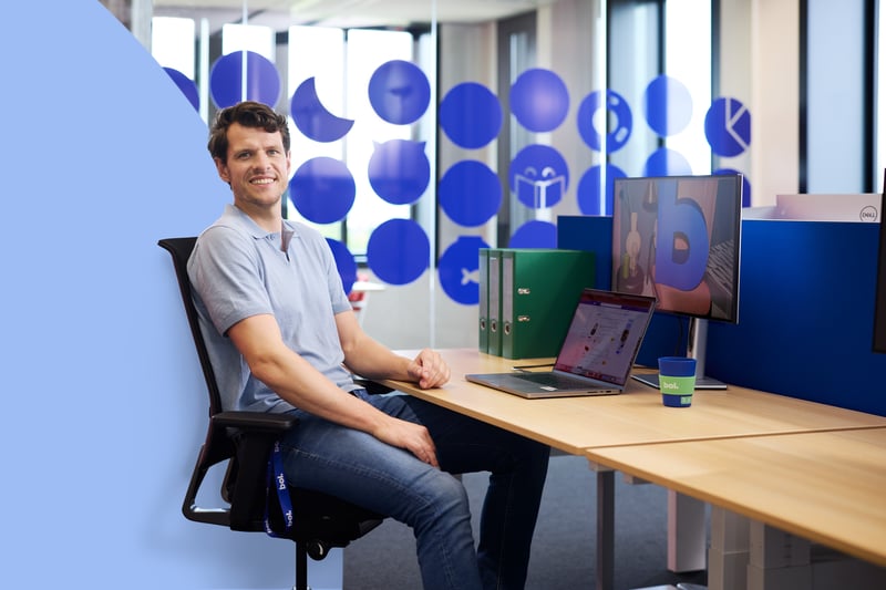 Een persoon zit achter een laptop aan een tafel te werken