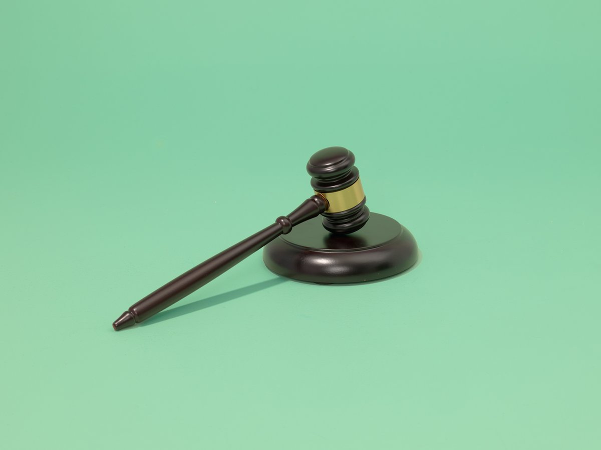 Houten rechtershamer met slagblok op een groene achtergrond.