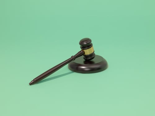 De hamer van een rechter op een groene achtergrond.