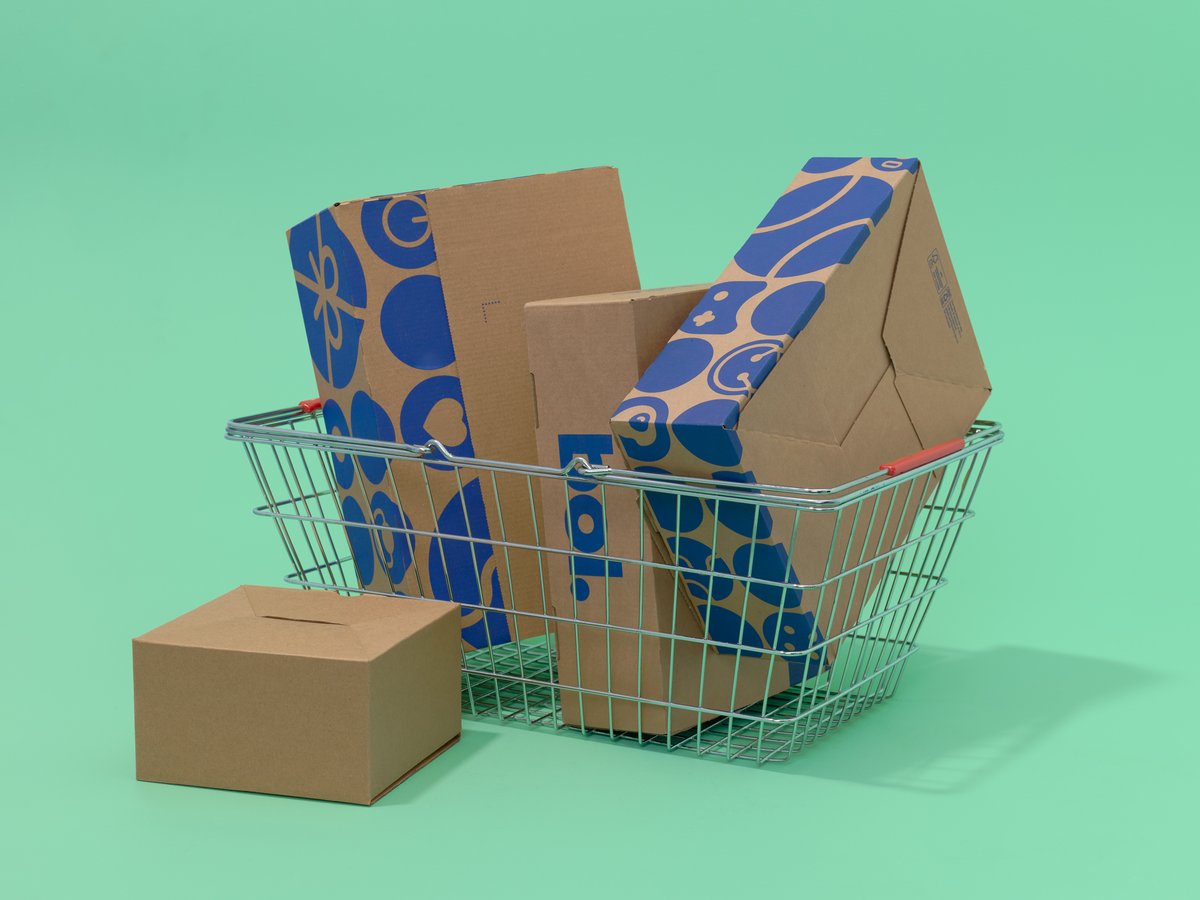 Een winkelmandje gevuld met bruine kartonnen dozen staat op een groene achtergrond.