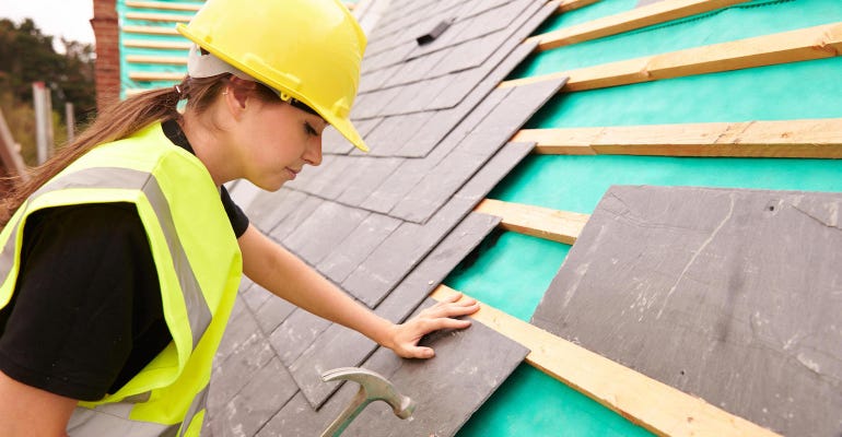 Female Construction Worker On Roofing Site Laying Slate Tiles